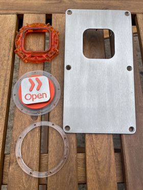 The button components and front plate, cleaned and looking very shiny. The button is orange once again, though the orange light ring is still quite dirty