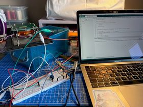 A Macbook is open next to the breadboard with the ESP32 connected via wires. The Macbook shows the Arduino IDE with the Hue switch code.