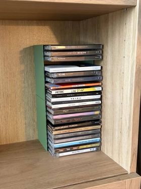 A stack of CDs in an olive green rack, on a bookshelf. From top to bottom: Coldplay - Parachutes, Carly Rae Jepsen - EMOTION, Franz Ferdinand, Keane - Under The Iron Sea, Keane - Perfect Symmetry, Keane - Strangeland, Keane - Cause and Effect, Metric - Live It Out, Metric - Pagans in Vegas, Metric- Synthetica, Metric - Romanticize The Dive, Missy Higgins - On A Clear Night, MUNA - Dancing Off The Wall, The Organ - Grab That Gun, Paramore - After Laughter, Red Hot Chili Peppers - By The Way, Tegan and Sara - So Jealous, Tegan and Sara - The Con, Tegan and Sara - Sainthood, Tegan and Sara - Heartthrob, Vampire Weekend, Yeah Yeah Yeahs - Show Your Bones, Yeah Yeah Yeah - It's Blitz!