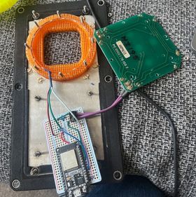 A deconstructed view of the button: the orange 3D printed ring in its setting on the metal panel, with an LED strip inside the channel that runs around the edge. The LED strip is wired into the prototype board and sits next to the button panel which is also wired into the prototype board.