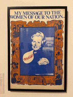 A 1980s artwork showing Margaret Thatcher with the words 'my message to the women of our nation' and a speech bubble coming from Thatcher's face saying 'TOUGH!'. The image of Thatcher is surrounded by illustrations describing ways in which her government has harmed women: hospitals closed, nurseries closed, council houses for sale, unemployment, £4,000,000,000 cut in public spending by 1981, elderly care centres closed, £308,000,000 cut from housing budget, fares increase, VAT up to 15%, £55,000,000 cut from education programme, gas and electricity up