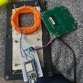 A deconstructed view of the button: the orange 3D printed ring in its setting on the metal panel, with an LED strip inside the channel that runs around the edge. The LED strip is wired into the prototype board and sits next to the button panel which is also wired into the prototype board.