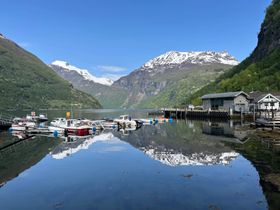 A view from the harbour of Geiranger in Norway, looking out over shimmering waters into the fjord.