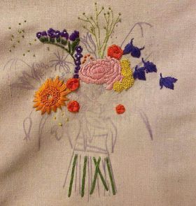 An embroidery in progress featuring statice, a peony, roses and a gerbera